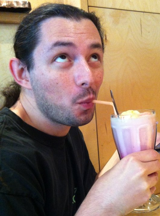 Photo of me sipping a large pink milkshake.